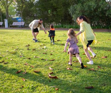 A joyful family playing together in a lush green park setting, enjoying a bright day.